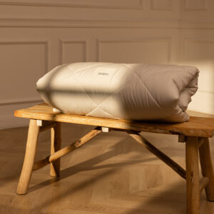 Kołdra marki Eraen w 100% z alpaki, złożona na drewnianej ławce